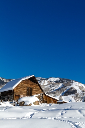 Historic Steamboat Springs barn on snowy hill with ski area lifts and slopes in backgroundのeditorial素材