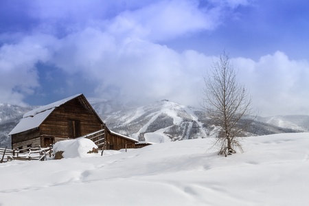 Historic Steamboat Springs barn on snowy hill with ski area lifts and slopes in backgroundのeditorial素材