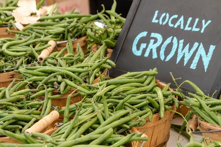 Bushel baskets full of locally grown green beans for sale at farmers market with chalkboard signの写真素材