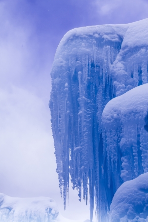 Looking up at sky at abstract ice and icicle formations on cold winter day after freshly fallen snowの写真素材