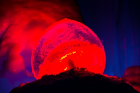 Glowing ice orb lit with red lights inside ice cave on cold winter eveningの写真素材