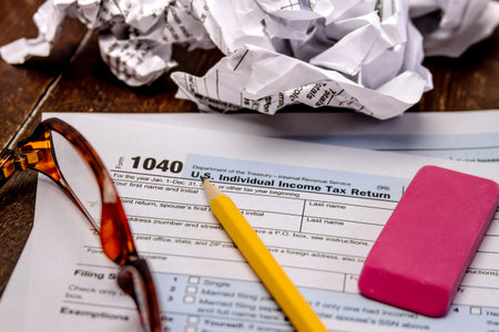 Tax form 1040 with crumpled up forms, glasses, pink eraser and pencil