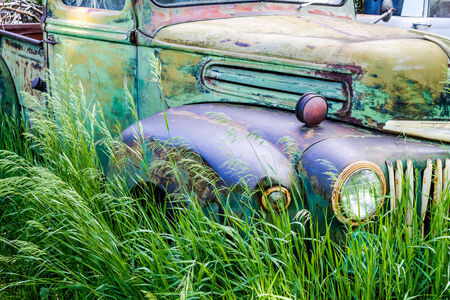 Close up of abandoned green and blue pickup truck rusting in a field on summer dayのeditorial素材