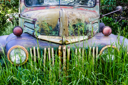 Close up of front of abandoned green and blue pickup truck rusting in a field on summer dayのeditorial素材