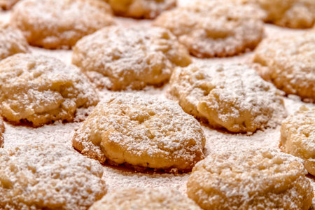 Rows of potato chip cookies sprinkled with powdered sugar sitting on wax paper