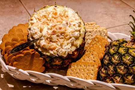 Fresh pineapple and toasted coconut dip garnished with macadamia nuts sitting in white basket with...