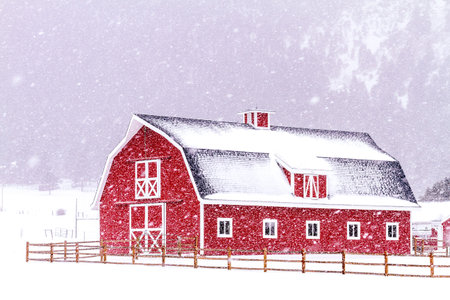 Bright red barn covered with snow surrounded with wooden fence on snowy winter dayのeditorial素材