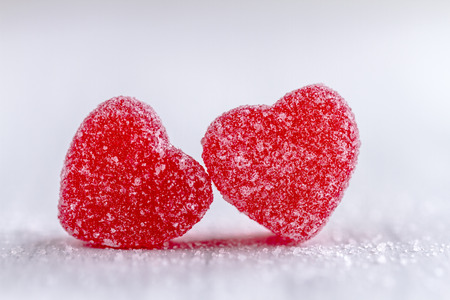 Two cinnamon heart candies coated with sugar sitting on white backgroundの写真素材