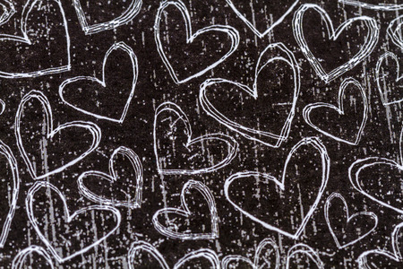 Black chalk board background with hand drawn white heartsの写真素材