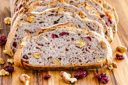 Close up of slices of walnut cranberry bread sitting on wooden cutting board