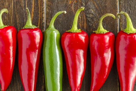 Close up of fresno peppers in row sitting on dark wooden table with one serrano pepperの写真素材