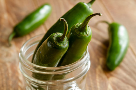Close up of serrano peppers standing in jar on wooden tableの写真素材