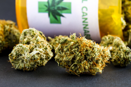 Close up of medical marijuana buds spilling out of prescription bottle with label on black backgroundの写真素材