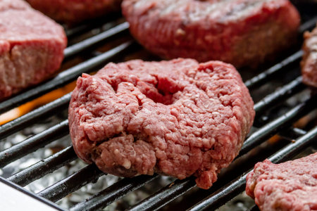 Close up of hamburger patties cooking on hot grill at summer picnic