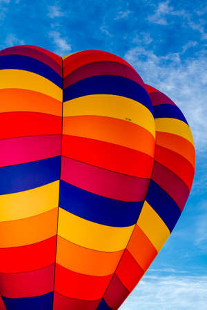 Brightly colored hot air balloon against blue morning sky on the ground before take offの写真素材