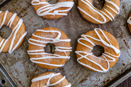 Close up of baking pan filled with homemade baked cinnamon pumpkin donuts with apple cider drizzleの写真素材