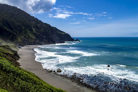 Scenic overlook overlooking a Pacific Ocean Beach with crashing waves and rocks on sunny afternoonの写真素材