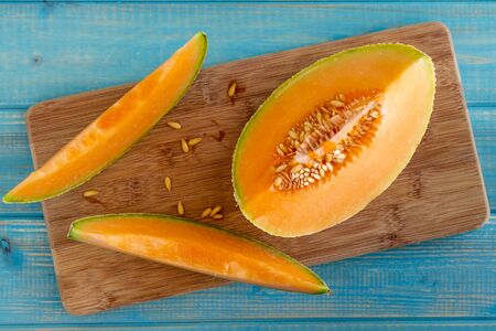Fresh organic cut cantaloupe melon slices siting on wooden cutting board with seedsの写真素材
