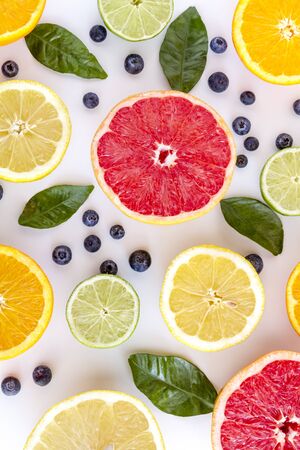 Fresh organic citrus fruits with blueberries sitting on white board with green leavesの写真素材