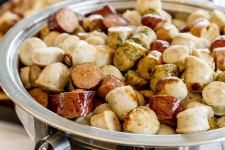 Assorted small sausage bites in catering dish on display at partyの写真素材