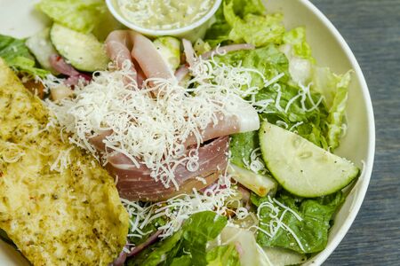 Close up of  healthy lunch Italian salad with romaine lettuce, cucumbers and onions with herb flatbread slice and dressing on the sideの写真素材