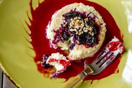 Vanilla cheesecake tart dessert topped with fresh blueberry sauce in raspberry puree shot from aboveの写真素材