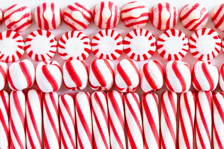 Horizontal close up of four types of red and white peppermint candies arranged in rowsの写真素材