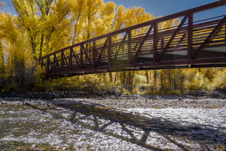 Bridge over Gunnison River on sunny fall afternoon with yellow trees lining the shoreの写真素材