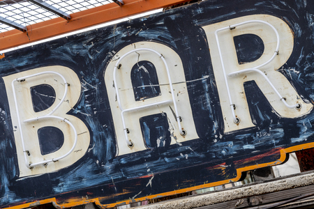 Grungy rusty old painted neon bar sign hanging in junkyardの写真素材