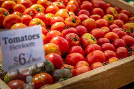 Wooden box display filled with fresh heirloom tomato varieties for sale at local farmers outdoor marketの写真素材
