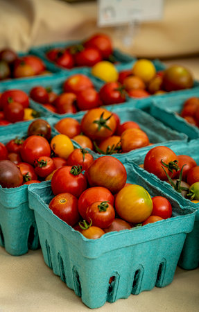 Display of locally grown fresh cherry tomatoes in blue paper containers for sale at local farmers marketの写真素材