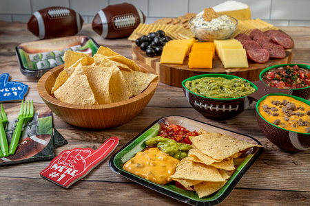Tailgating football party food display with tortilla chips, guacamole, salsa, and queso dips and meat, cheese and cracker tray ready for game day partyの写真素材