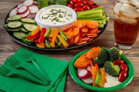 Vegetable platter with variety of cut vegetables surrounding bowl filled with ranch dressing dip and a glass of ice tea to drinkの写真素材