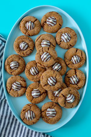 Gingerbread blossom holiday cookies, with white chocolate striped candy on blue oval plate with gray striped napkins on left sideの写真素材