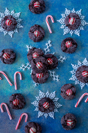 Cookie display of peppermint chocolate blossom cookies on white glitter snowflakes with small candy canes, sitting on bright blue abstract backgroundの写真素材