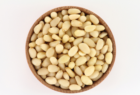 Pine nuts in a round wooden form on a white backgroundの写真素材