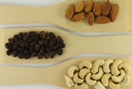 Abstract view of wooden shovels with mixed nuts on a white backgroundの写真素材