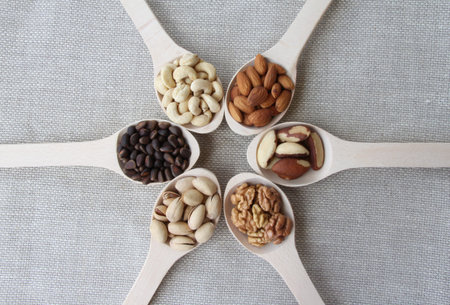 Abstract view of a wood spoon with mixed nuts on a background of natural fabricsの写真素材
