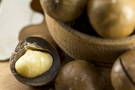 Macadamia nuts in shell and without it on the background of woodの写真素材