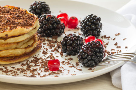 Pancakes sprinkled with chocolate chips with red currants and blackberriesの写真素材