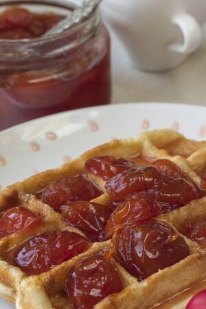 Waffles with jam from a plum on a white plateの写真素材