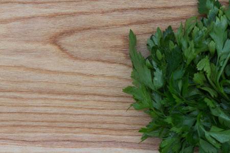 Fresh greens on the background of a wooden kitchen (brushed) board. Top view.