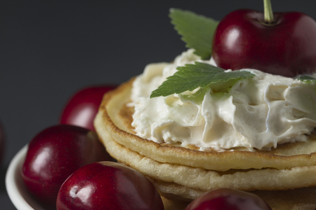 Pancakes with cherries and whipped cream on a black backgroundの写真素材