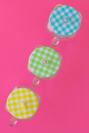 Creative look at the colored jars for a summer cold drink on a pink background. Top view.