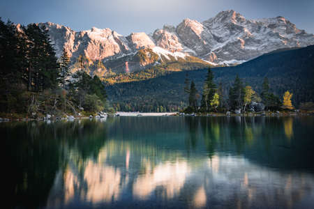 Photo Eibsee in the municipality of Grainau with the Wetterstein Mountains, forest and the Zugspitze at sunset. The Eibsee is a popular destination in Bavaria below the Zugspitze.の写真素材