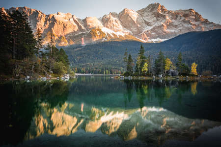 Photo Eibsee in the municipality of Grainau with the Wetterstein Mountains, forest and the Zugspitze at sunset. The Eibsee is a popular destination in Bavaria below the Zugspitze.の写真素材