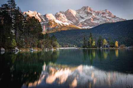 Photo Eibsee in the municipality of Grainau with the Wetterstein Mountains, forest and the Zugspitze at sunset. The Eibsee is a popular destination in Bavaria below the Zugspitze.の写真素材
