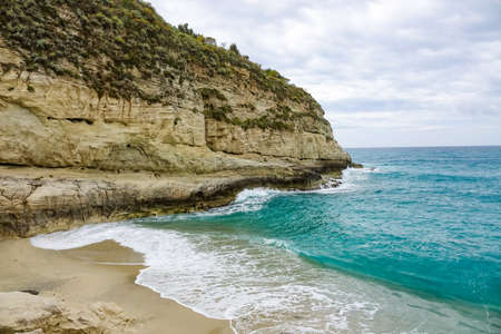 Amazing tropical panoramic view of turquoise bay, sandy beach, green mountains and plants, blue sky, white clouds background, Capo Vaticano rock platform, Calabria, southern Italy.の写真素材