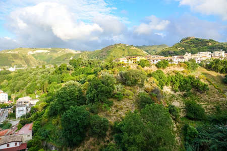 Amazing tropical panoramic view of turquoise bay, sandy beach, green mountains and plants, blue sky, white clouds background, Capo Vaticano rock platform, Calabria, southern Italy.の写真素材
