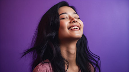 Portrait of a beautiful young asian woman smiling on purple backgroundの素材